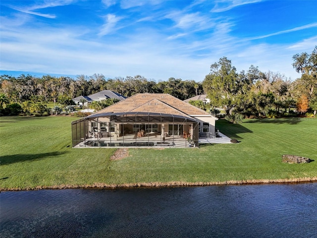 rear view of property with a lawn, a lanai, a water view, and a patio area