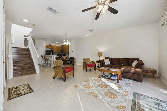 tiled living room featuring ceiling fan with notable chandelier