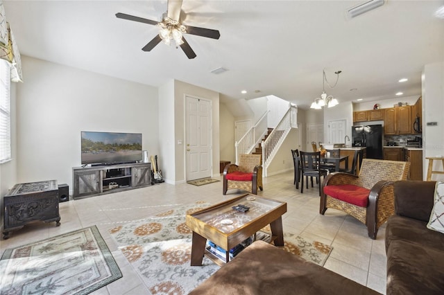 tiled living room featuring ceiling fan with notable chandelier and sink