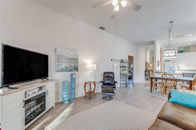 living room with light hardwood / wood-style floors and ceiling fan with notable chandelier