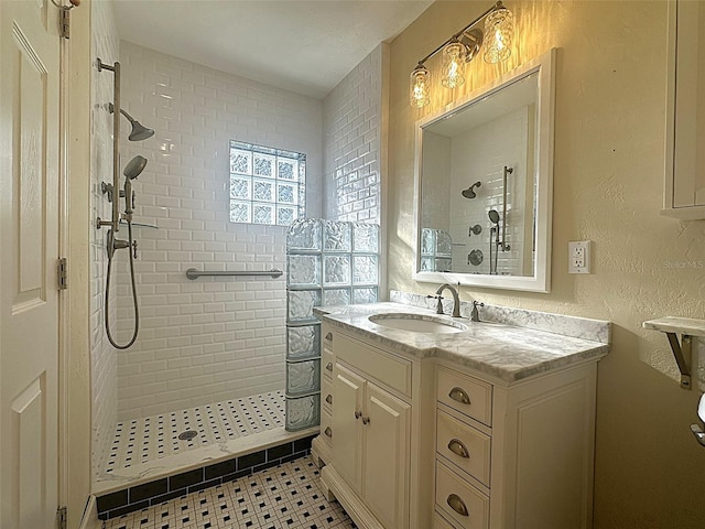 bathroom with tiled shower, vanity, and tile patterned flooring