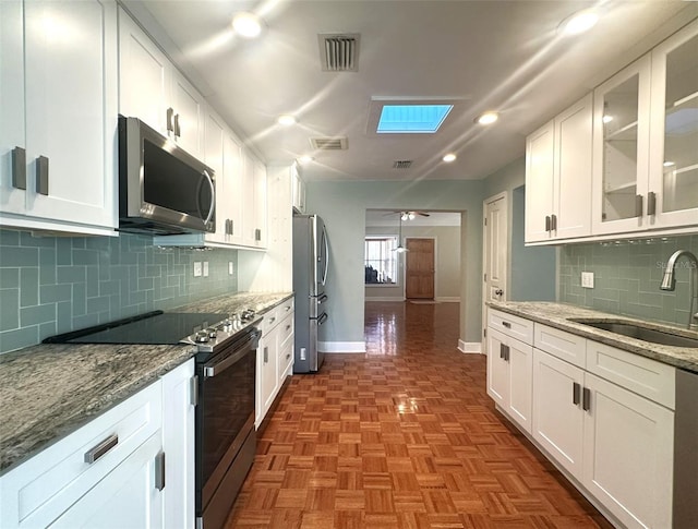 kitchen featuring sink, ceiling fan, stainless steel appliances, light stone countertops, and white cabinets