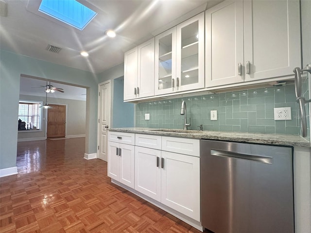 kitchen with sink, tasteful backsplash, stainless steel dishwasher, light stone countertops, and white cabinets