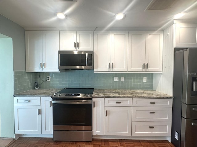 kitchen featuring white cabinetry, stainless steel appliances, light stone countertops, and decorative backsplash