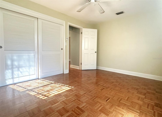 unfurnished bedroom featuring parquet flooring, ceiling fan, and a closet