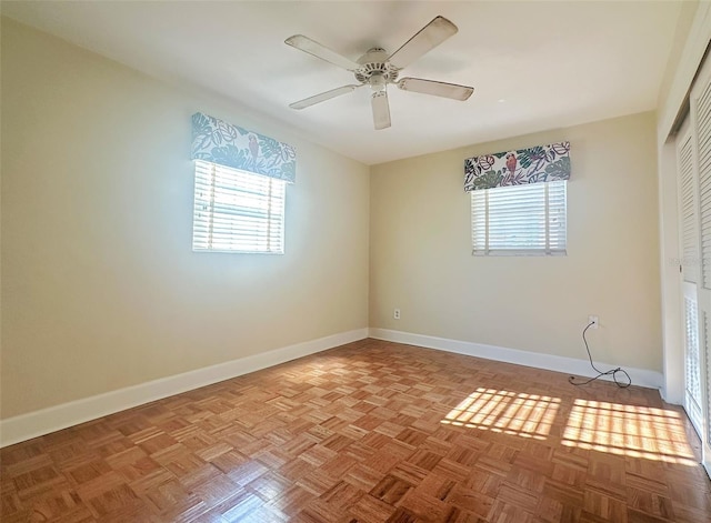 empty room with a healthy amount of sunlight, ceiling fan, and light parquet flooring