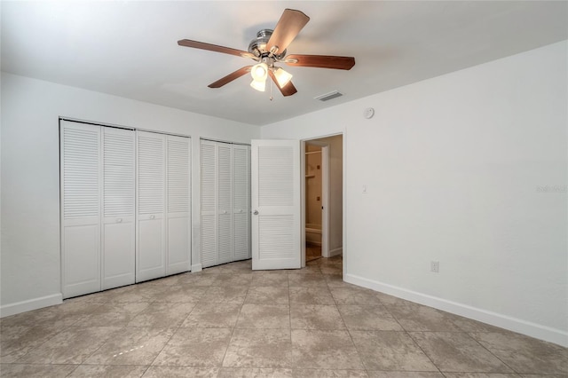 unfurnished bedroom with multiple closets and ceiling fan