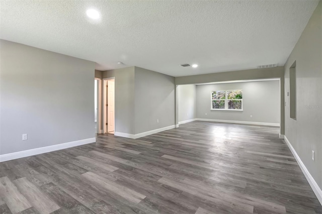 empty room with dark hardwood / wood-style floors and a textured ceiling