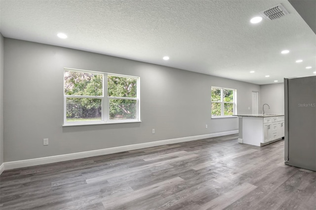 unfurnished room featuring hardwood / wood-style floors, sink, and a textured ceiling