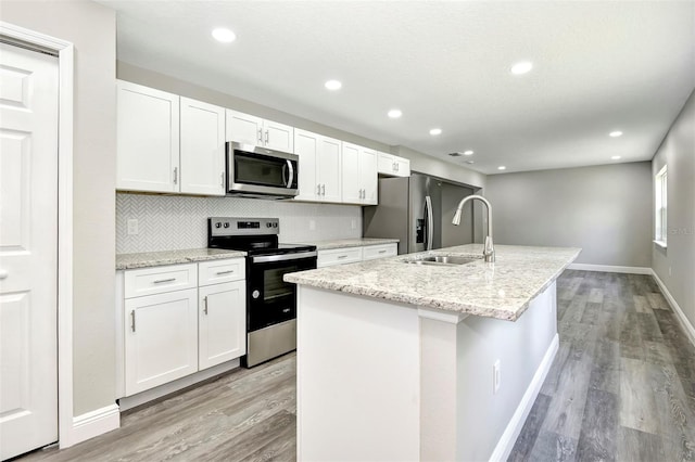 kitchen with white cabinetry, sink, an island with sink, light hardwood / wood-style floors, and appliances with stainless steel finishes