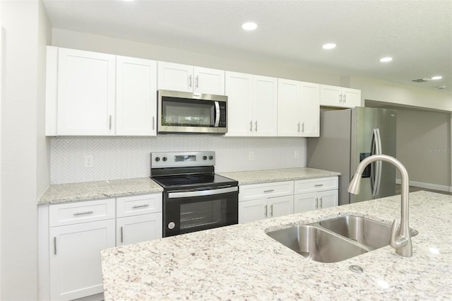 kitchen featuring white cabinets, stainless steel appliances, light stone countertops, and sink