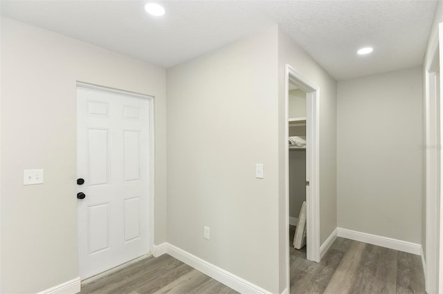 corridor with a textured ceiling and light hardwood / wood-style flooring