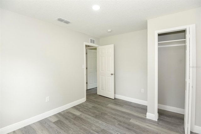 unfurnished bedroom featuring a textured ceiling, hardwood / wood-style flooring, and a closet