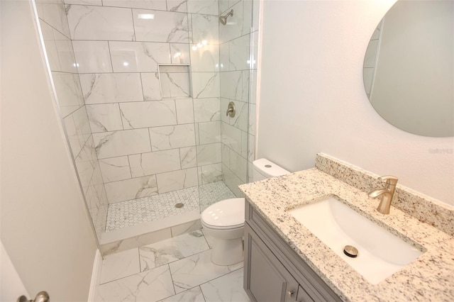 bathroom featuring vanity, toilet, and a tile shower