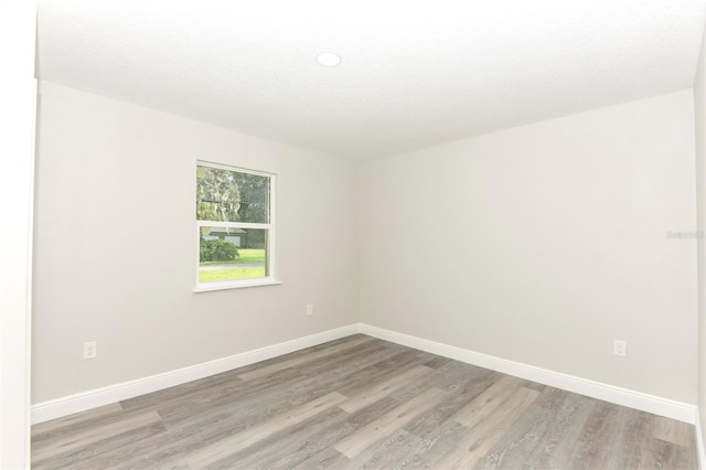 spare room with a textured ceiling and light wood-type flooring