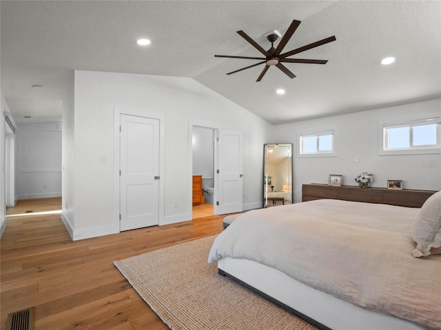 bedroom with a textured ceiling, ensuite bath, vaulted ceiling, ceiling fan, and light hardwood / wood-style flooring