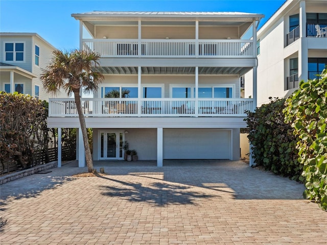 coastal inspired home with french doors, a balcony, and a garage