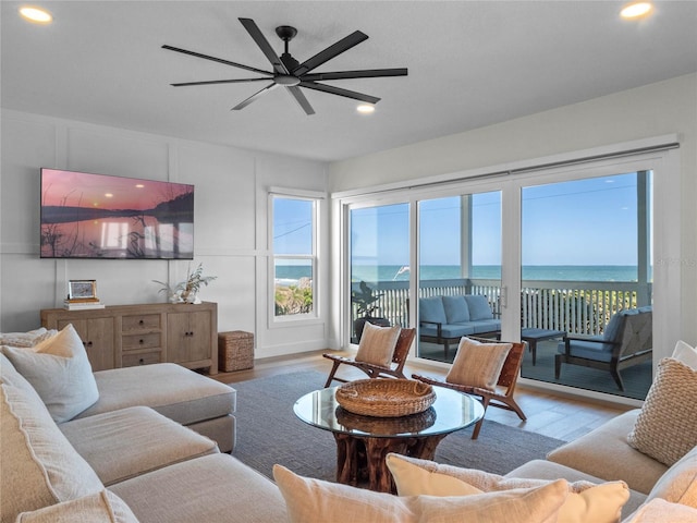 living room featuring ceiling fan, hardwood / wood-style floors, and a water view