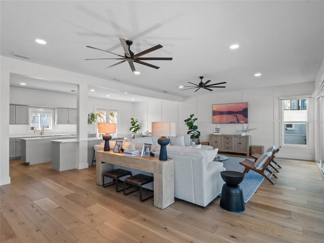 living room with ceiling fan, a healthy amount of sunlight, and light hardwood / wood-style flooring