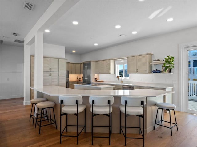 kitchen featuring light wood-type flooring, dishwasher, a large island, and a breakfast bar