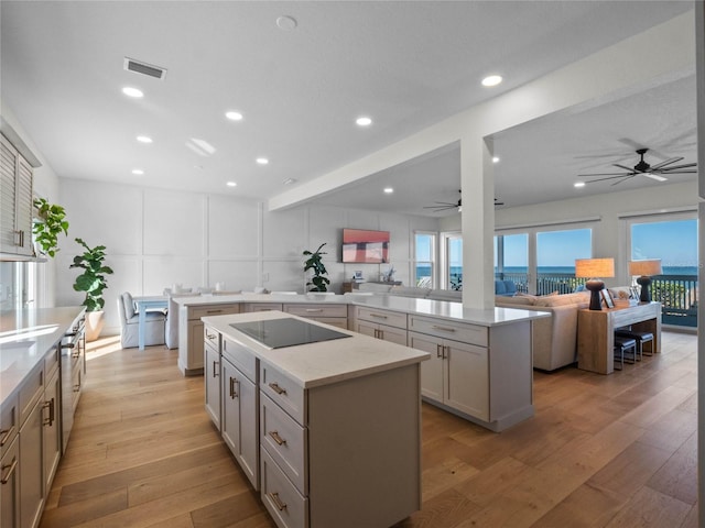 kitchen featuring a kitchen island, black electric stovetop, light hardwood / wood-style flooring, and kitchen peninsula