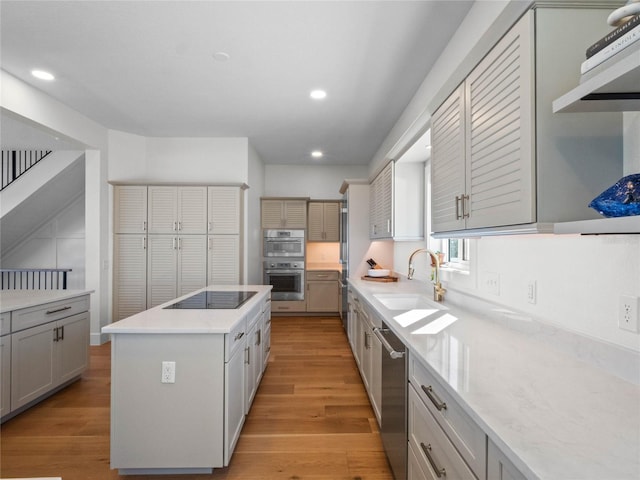 kitchen featuring sink, a kitchen island, light hardwood / wood-style flooring, stainless steel appliances, and gray cabinets