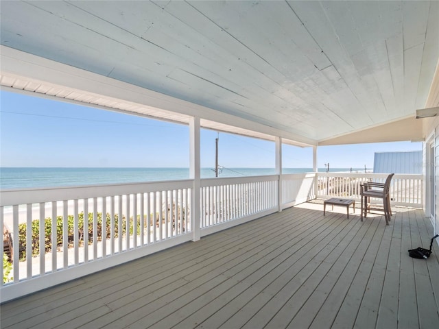 wooden terrace featuring a water view and a view of the beach