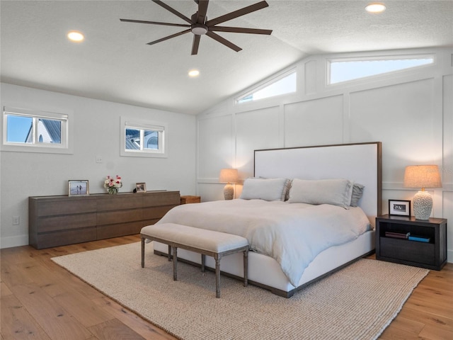 bedroom with ceiling fan, a textured ceiling, vaulted ceiling, and light wood-type flooring