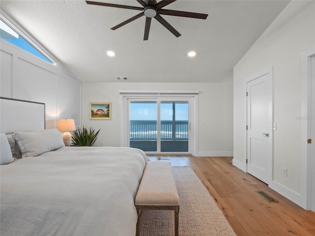 bedroom with vaulted ceiling, ceiling fan, access to outside, light wood-type flooring, and multiple windows