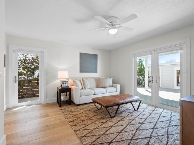 living room with plenty of natural light, light hardwood / wood-style floors, ceiling fan, and french doors