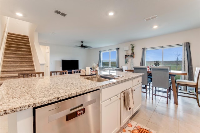 kitchen featuring stainless steel dishwasher, light stone counters, ceiling fan, white cabinets, and light tile patterned flooring