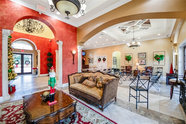 tiled living room featuring french doors, ornate columns, ornamental molding, a tray ceiling, and an inviting chandelier