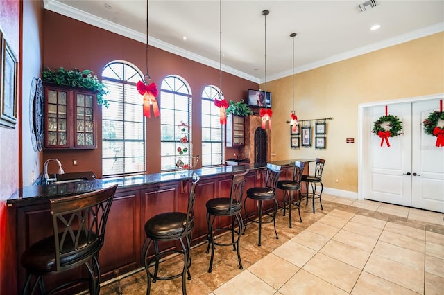 bar with crown molding, sink, light tile patterned floors, and decorative light fixtures