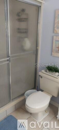 bathroom featuring toilet, tile patterned floors, and an enclosed shower