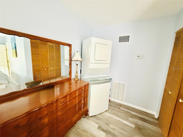 824 Garfish Ave, New Smyrna Beach, FL 32169 - laundry room with stacked washer / dryer, light wood-style floors, and baseboards
