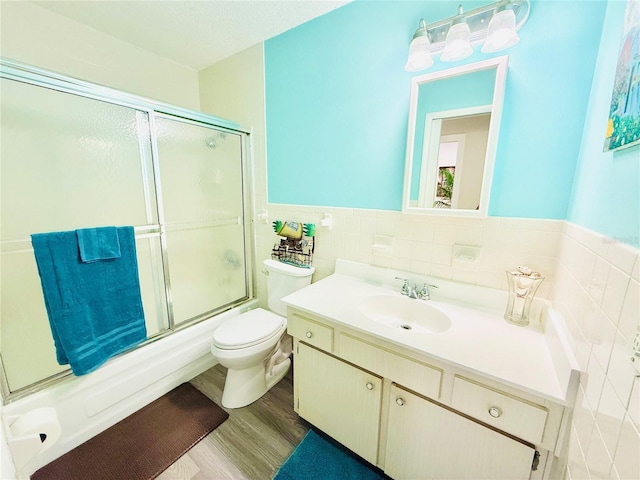 824 Garfish Ave, New Smyrna Beach, FL 32169 - bathroom featuring tile walls, vanity, combined bath / shower with glass door, wood finished floors, and toilet
