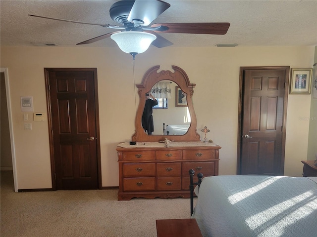 bedroom featuring ceiling fan, light colored carpet, and a textured ceiling