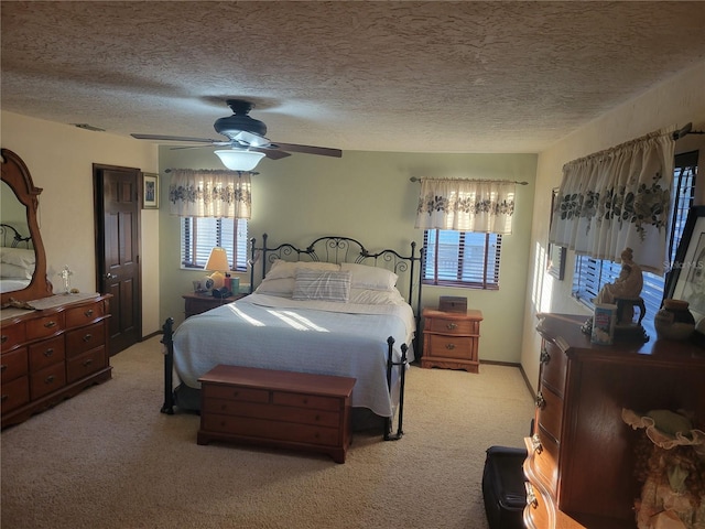 bedroom with ceiling fan, light colored carpet, and a textured ceiling