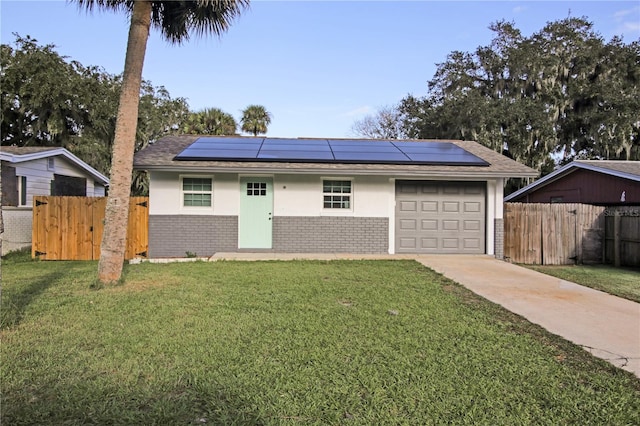 single story home featuring a front yard, solar panels, and a garage