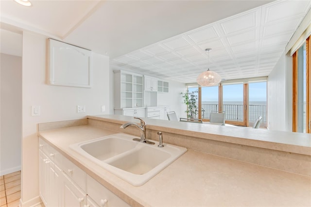 5201 S Atlantic Ave Unit 809A, New Smyrna Beach, FL 32169 - kitchen featuring a sink, a water view, white cabinets, and hanging light fixtures