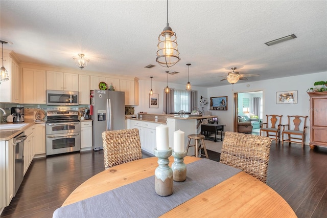 dining space featuring a textured ceiling, dark hardwood / wood-style flooring, ceiling fan, and sink