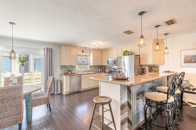 kitchen with kitchen peninsula, appliances with stainless steel finishes, dark hardwood / wood-style floors, and a breakfast bar area