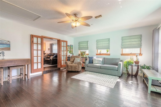 living room with dark hardwood / wood-style flooring, ceiling fan, french doors, and a textured ceiling