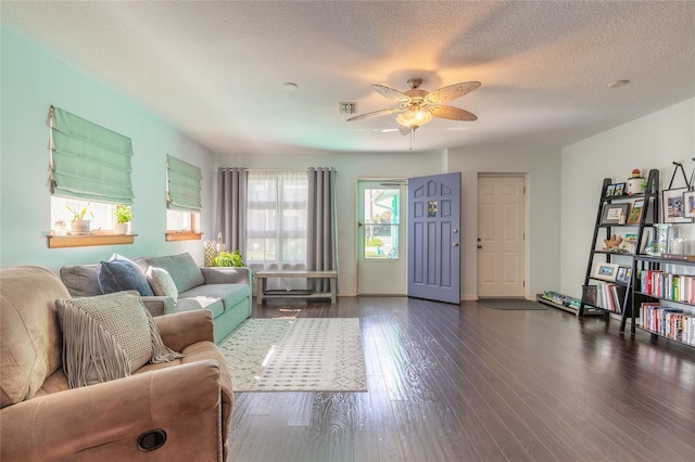 living room featuring ceiling fan, dark hardwood / wood-style flooring, and a textured ceiling