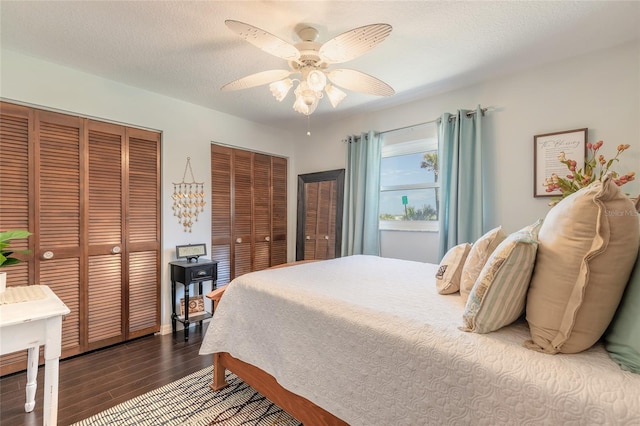 bedroom with hardwood / wood-style flooring, ceiling fan, a textured ceiling, and two closets