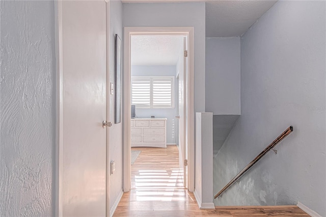 hallway with a textured ceiling and light wood-type flooring