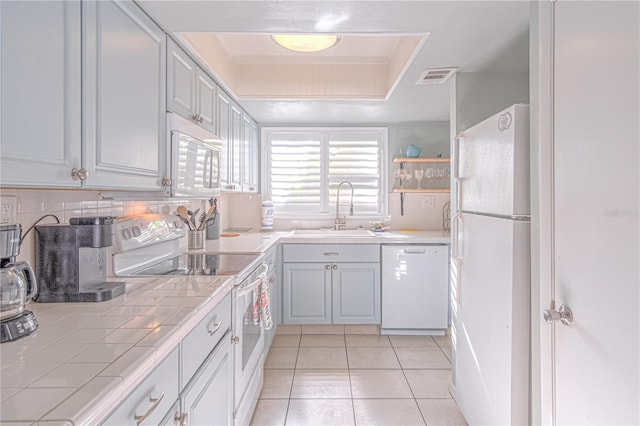 kitchen with white appliances, backsplash, sink, light tile patterned floors, and tile counters