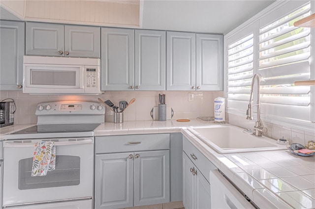 kitchen featuring decorative backsplash, white appliances, tile counters, and sink