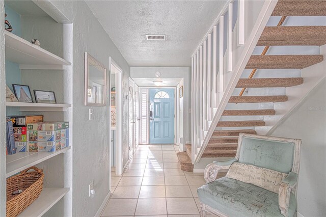 foyer entrance featuring light tile patterned flooring and a textured ceiling