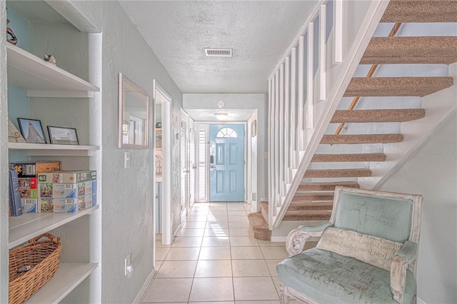 4017 Saxon Dr, New Smyrna Beach, FL 32169 - entryway featuring a textured ceiling, tile patterned floors, stairway, and a textured wall